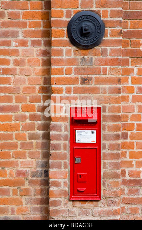 Un VR (Victorian) Lettre Post Box encastré dans le mur d'un bâtiment en briques rouges à Snape Maltings, Suffolk, Angleterre, RU Banque D'Images