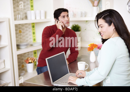 Portrait of a Mid adult woman using a Laptop with a young man talking on a mobile phone Banque D'Images