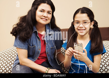 Portrait of a young woman with her daughter de l'écoute d'un mp3 player Banque D'Images
