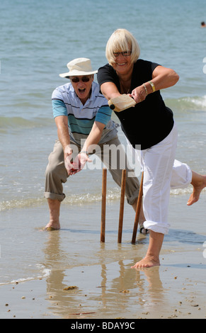 L'homme et la femme à jouer au cricket sur la plage couple de retraités bénéficiant d'exercice sain sur la plage Banque D'Images