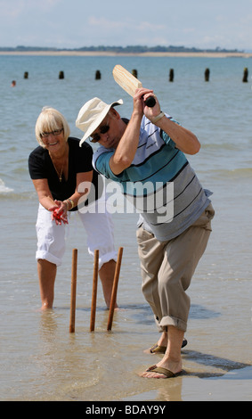 L'homme et la femme à jouer au cricket sur la plage couple de retraités bénéficiant d'exercice sain sur la plage Banque D'Images