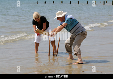 L'homme et la femme à jouer au cricket sur la plage couple de retraités bénéficiant d'exercice sain sur la plage Banque D'Images