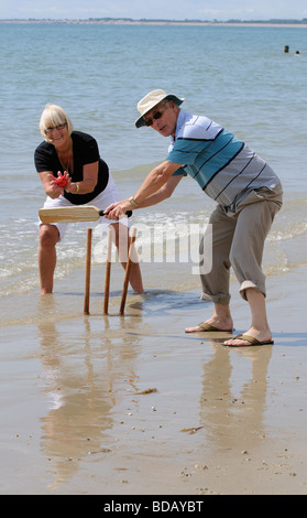 L'homme et la femme à jouer au cricket sur la plage couple de retraités bénéficiant d'exercice sain sur la plage Banque D'Images