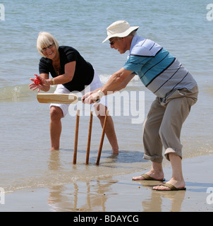 L'homme et la femme à jouer au cricket sur la plage couple de retraités bénéficiant d'exercice sain sur la plage Banque D'Images