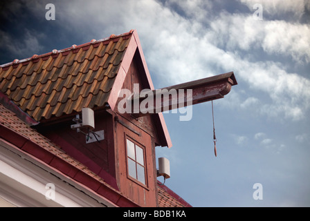 Construction de levage sur le vieux toit de maison avec petite fenêtre et ciel nuageux comme arrière-plan. Détail de l'architecture ancienne. Banque D'Images