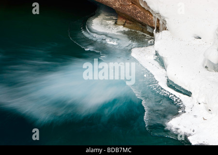 Lower Falls partiellement gelé de la Johnston Creek pendant l'hiver avec de l'eau qui s'écoule dans un bassin à la base entourée de glace Banque D'Images