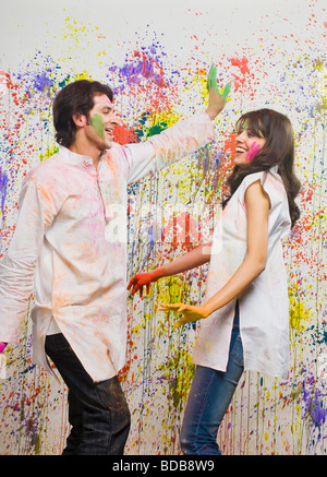 Couple danser devant un mur de couleur avec les couleurs d'Holi Banque D'Images