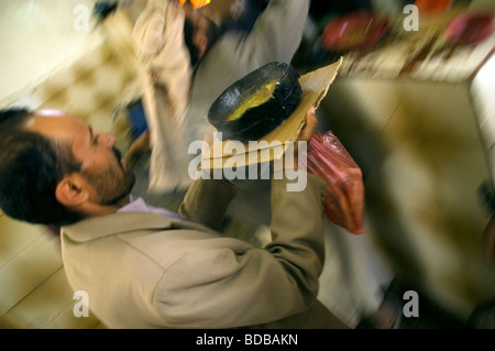 Un garçon porte un plat de viande en ragoût traditionnel yéménite connu sous le nom de 'salta' à humayda salta restaurant situé dans la région de Sanaa, Yémen. Banque D'Images