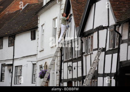 Un peintre au travail sur une maison de la rue Mill à Warwick UK Banque D'Images