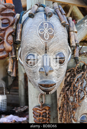 Une main remarquable en bois sculpté et peint masque tribal africain en blanc attaché avec d'autres chef décoration avec chaîne. Banque D'Images