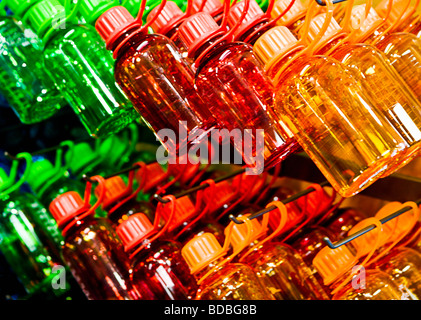 Les bouteilles en plastique, de couleur rouge, orange et vert empilés et accroché dans une rangée, montrant. Banque D'Images