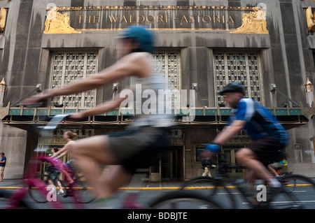 New York City, NY aux cyclistes de rouler au-delà de l'hôtel Waldorf Astoria de Park Avenue, au cours de l'été Rue Banque D'Images