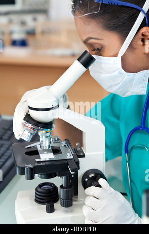 Une femme d'origine asiatique médecin ou chercheur scientifique à l'aide de son microscope dans un laboratoire Banque D'Images