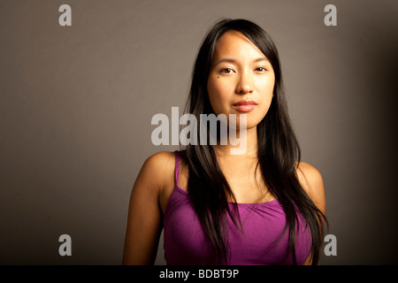 Portrtait de femmes philippines portant chemisier violet contre l'arrière-plan gris, sérieux. Banque D'Images