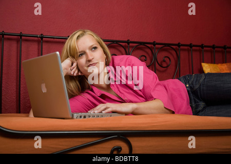 Girl lying on a bed with her laptop Banque D'Images