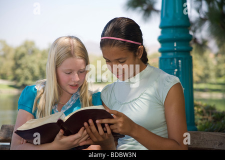 Deux filles racialement mixtes 2 lecture la diversité ethnique Caucasien hispanique discuter Bible naturel nature jeune personne de personnes 11 12 13 ans ans Myrleen Pearson Banque D'Images