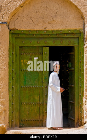 Jeune homme en face de maison traditionnelle faite de boue et de brique dans la ville d'Al Hamra Sultanat d'Oman Banque D'Images