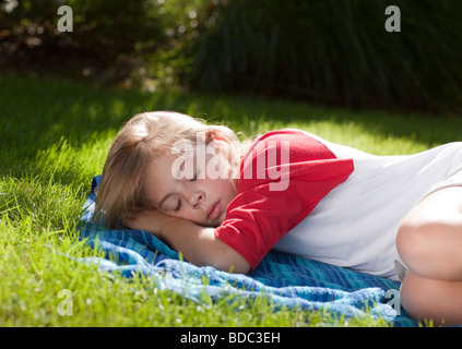 Jeune fille endormie sur une pelouse Banque D'Images