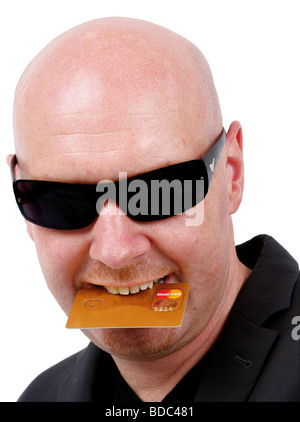 L'homme à la tête chauve avec des lunettes et une carte de crédit dans la bouche Banque D'Images