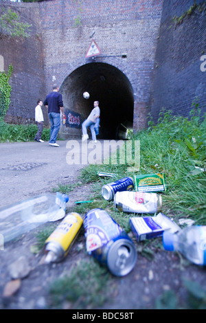 Litière de jeunes fumeurs des canettes de bière à jouer au football par tunnel ferroviaire Banque D'Images