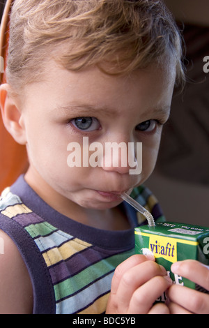 Bébé garçon carton potable de jus de pomme Banque D'Images