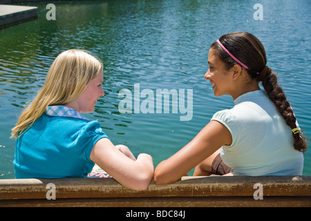 Deux filles de la Californie d'interpolations de Tween hang traînant ensemble Hispanic Woman junior high pour siéger au banc de parc converse parler. 11-13 ans o Banque D'Images