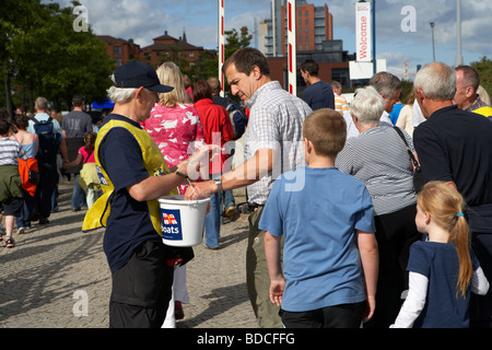 Faire du bénévolat pour un organisme de collecte de godet le RNLI à un événement en plein air à Belfast en Irlande du Nord uk Banque D'Images