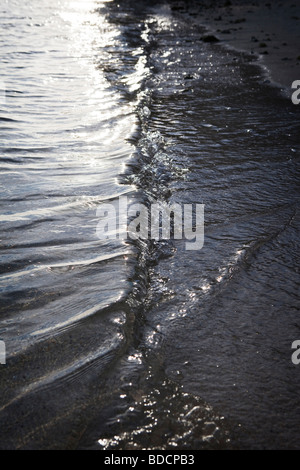 Vagues roulant sur une plage au coucher du soleil de Rarotonga aux îles Cook dans le Pacifique Sud Banque D'Images