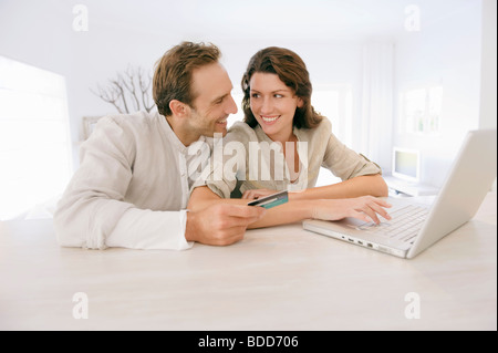 Couple holding d'une carte de crédit et de travail sur un ordinateur portable Banque D'Images