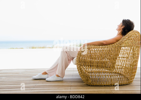 Femme couchée sur une chaise sur la plage Banque D'Images