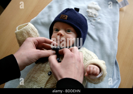 Un enfant âgé d'un mois s'est terminée au chaud par maman prêt à aller à l'extérieur. Parution du modèle Banque D'Images