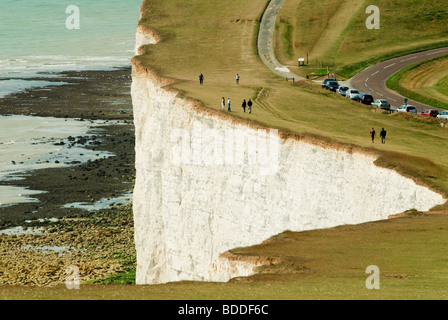 Personnes marchant près du bord de la falaise de craie blanche à Beachy Head Eastbourne Angleterre donnant sur la Manche Banque D'Images