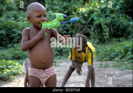 Les enfants portant des dons de charité T-shirts football et jouer avec les jouets de l'ouest dans un village pygmée, au Gabon. Banque D'Images