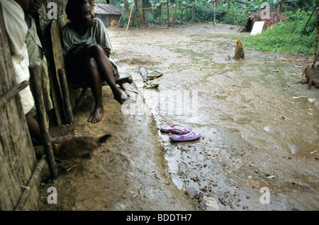 Un groupe de Pygmées Baka un abri contre une pluie diluvienne dans leur village au fin fond de la forêt tropicale d'Afrique centrale, le Gabon. Banque D'Images