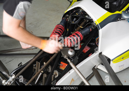 Mains de mécanicien travaillant sur l'installation de l'amortisseur sur un open wheeler voiture de course. Banque D'Images