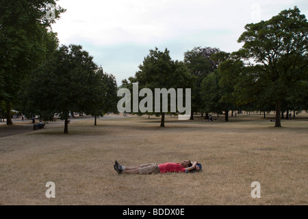 Un homme dormir sur un jour étés sur Hyde Park à Londres. Banque D'Images