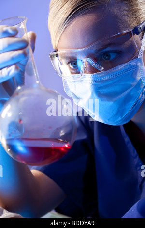 Une femme chercheur scientifique ou médical ou le médecin à une fiole de liquide rouge dans un laboratoire. Banque D'Images