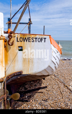 Un petit bateau de pêche en bois traditionnels (toujours en usage) nommé "Lowestoft" reposant sur la plage de galets à Aldeburgh, dans le Suffolk, UK. Banque D'Images