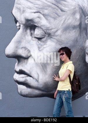 Pose de touristes chinois à côté de murales nouvellement repeint Andrei Sakharov par Dmitry Vrubel sur mur de Berlin à l'East Side Gallery Banque D'Images