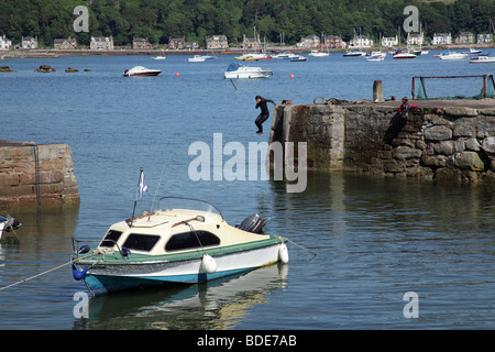 Enfant sautant dans le port depuis Millport Pier sur l'île de Great Cumbrae dans le Firth de Clyde, Ayrshire, Écosse, Royaume-Uni Banque D'Images