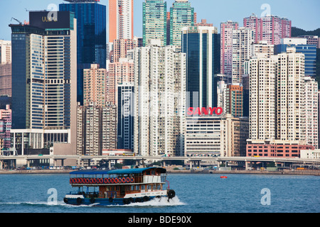 Voile en face de bâtiments de grande hauteur dans le port de Victoria, Hong Kong, Chine. Banque D'Images