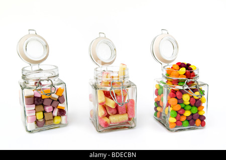 Portrait d'un mélange de bonbons dans trois pots de verre sur un fond blanc. Banque D'Images