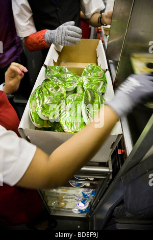 Membre de l'équipage de cabine avec chauffage par le repas dans la cuisine sur un avion en vol de Virgin Atlantic à Londres de Mumbai, Inde. Banque D'Images