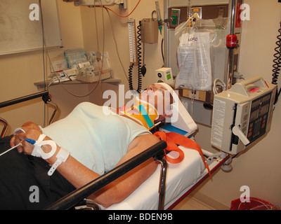 Une femme qui était dans un accident de voiture en salle d'urgence d'un hôpital de retenue sur une table d'examen avec retenue au cou Banque D'Images