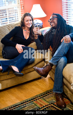 L'Interracial couple sitting on sofa in living room Banque D'Images