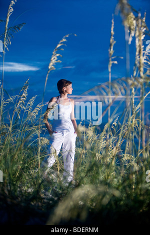 Jeune femme debout sur les dunes de sable de plage au crépuscule Banque D'Images