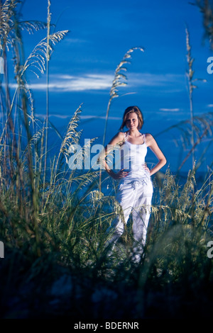 Jeune femme debout sur les dunes de sable de plage au crépuscule Banque D'Images