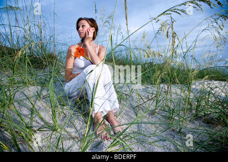 Jolie jeune femme assise sur la plage de dunes de sable et de la mer l'avoine Banque D'Images