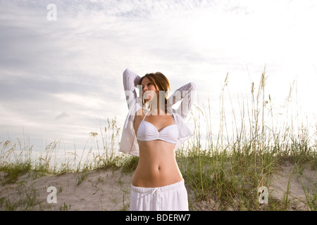 Young woman in white bikini top et jupe standing on beach Banque D'Images