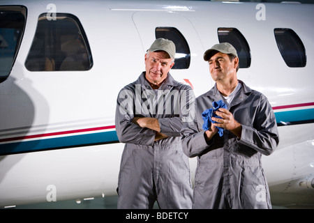 Deux mécaniciens avion debout à côté de petits avions dans le hangar Banque D'Images